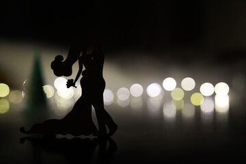 Black silhouettes of pair dancers performing. Man and woman are dancing on gray background with...