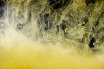clouds of yellow smoke on a black background, clouds of paint in water, aquarium, abstract...