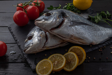 Sea bream or dorado sea fish herbs on dark slate background Top view 