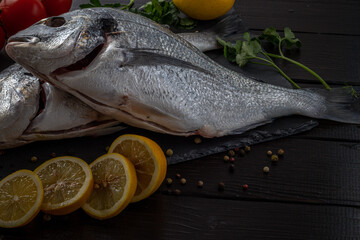 Sea bream or dorado sea fish herbs on dark slate background Top view 