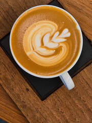 Nice Texture of Latte art on hot latte coffee . Milk foam in heart shape leaf tree on top of latte art from professional barista artist.