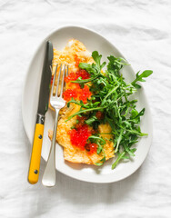 Cheese omelet with red caviar and arugula on a light background, top view - 784244395