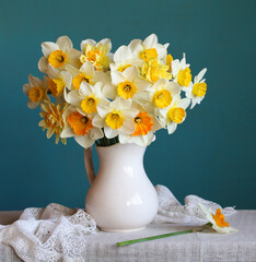 bouquet of garden daffodils in a white jug on the table, spring flowers.