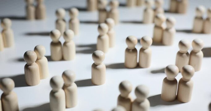Wooden figures of people in a crowd and one lonely person