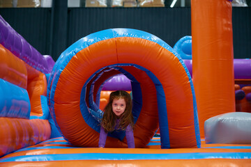 Cute girl playing on inflatable bounce house in entertainment center