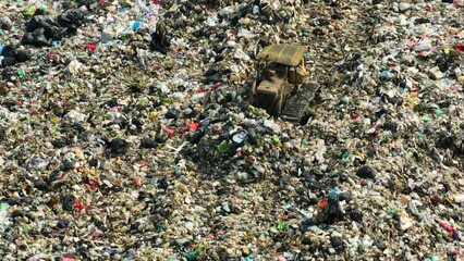 From above, a landfill sprawls, a mosaic of waste. A lone bulldozer toils amidst a kaleidoscope of hues, blending plastic, fabric, and assorted refuse in a chaotic dance.
- Powered by Adobe