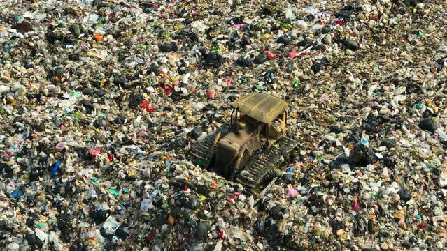 In a desolate wasteland of discarded dreams, a lone yellow bulldozer navigates through the tangled maze of refuse, its relentless determination a beacon of hope amidst the sea of decay.
