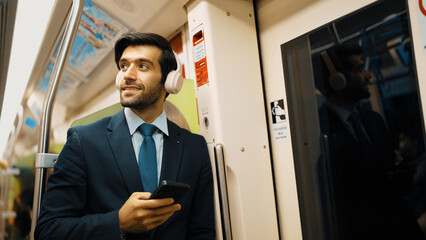 Smart executive manager wear headphone and listen music while standing in train. Professional...