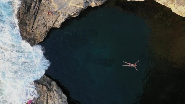 Slow motion aerial view of girl floating in Giola natural sea pool Thassos island, Greece