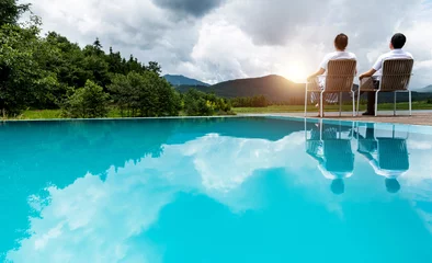 Papier Peint photo Turquoise Couple sitting on swimming poolside