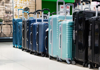 A customer chooses a suitcase for luggage in a department store. Buying small luggage for a...
