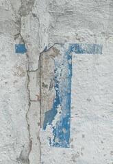 Textured cement wall, painted in white and up on it - damaged, faded out remains of letter or digit (blue paint). Also, the visible joint of concrete slabs (near the middle, to the left). 