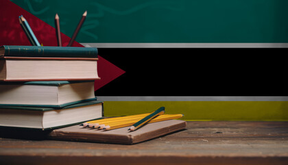 Books and pencils in classroom on the background of the Mozambique flag. Concept of education, back to school