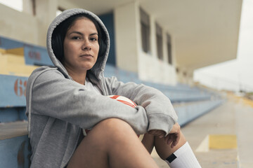 Young woman with soccer ball listening music through in headphones