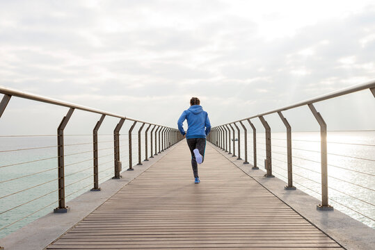 Rear view of a fit woman running seaside on a promenade