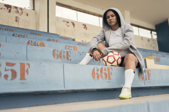 Young woman with soccer ball listening music through in headphones