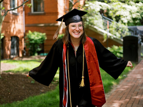 Exuberant graduate in cap and gown outdoors.