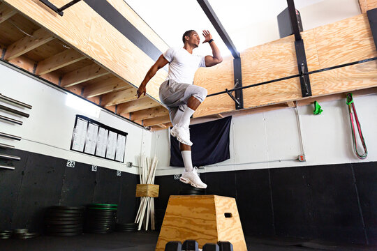 Fit Man Doing Box Jumps in Gym Next to Weights