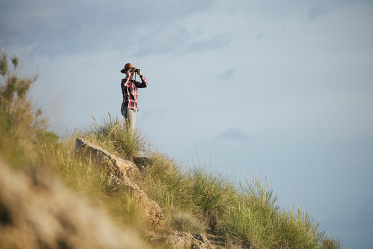 Woman with hat and plaid outfit watching the desert.