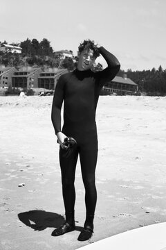 Male surfer taking a break on the beach after surfing