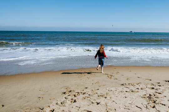 Girl running into ocean wearing clothes