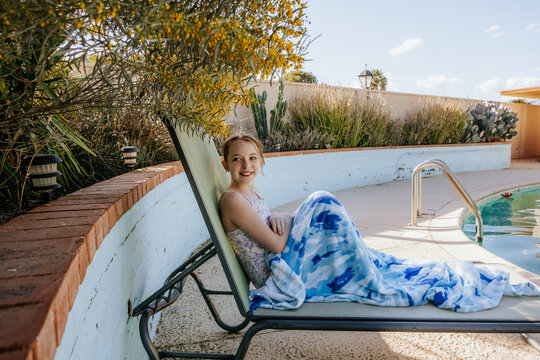 Happy tween girl sitting in pool chair on sunny day