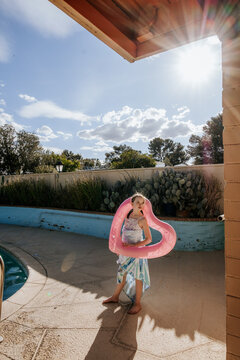 Girl holding pool float on sunny afternoon