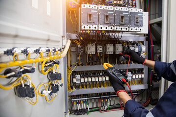 Electricity and electrical safety maintenance service system, Technician hand checking electric current voltage at circuit breaker terminal and cable wiring in main power distribution board.