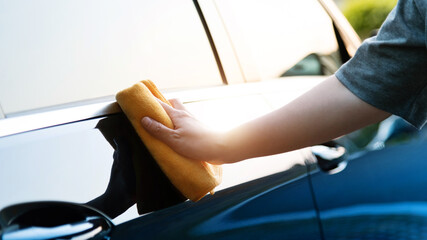 Woman hand cleaning car with a cloth