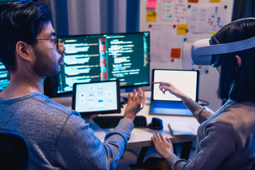 asian and Indian Developer  devops team testing  virtual reality coding promgram app at night in...