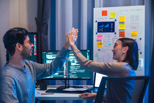 asian and Indian Developer team clapping hand for project success  with software computer at night in office
