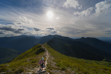 A mother and her little daughter walk high in the Tatra Mountains in the Carpathians on a sunny...