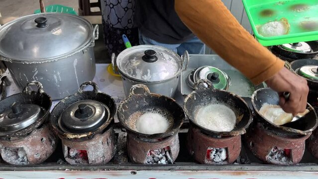 The process of making traditional dessert named Serabi made from rice flour and coconut milk by an old man with charcoal stove