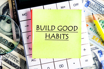 BUILD GOOD HABITS motivational concept text on a yellow sticker on the calculator against the background of banknotes