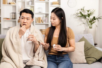 Caring woman giving medicine to sick man at home, couple showing support and health care