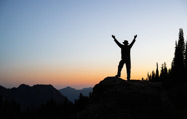 Silhouette image of a man raising arms at sunset. Paradise. Mount Rainier National Park. Washington...