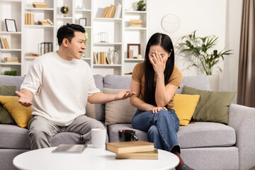 Couple Argument At Home, Man Gesticulating To Distressed Woman On Couch, Emotional Discussion, Family Conflict, Indoor Stressful Conversation, Relationship Issues