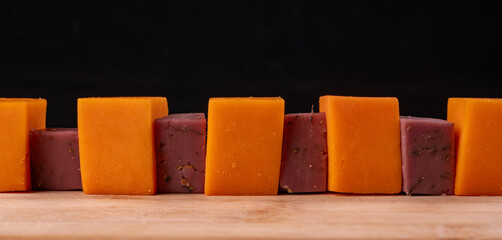 Cubes of orange and lavender cheese, alternating, lie on the table.