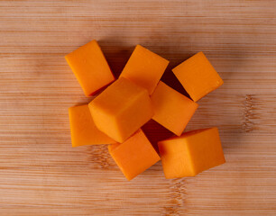 Pieces of orange cheese lie on a cutting board.