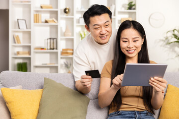Asian couple shopping online on tablet at home, man holding credit card, happy, technology, e-commerce