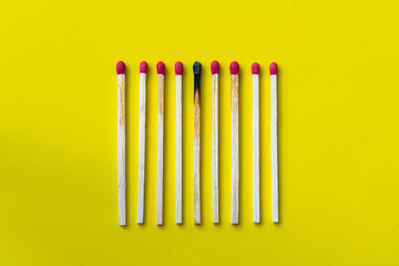 Success, defeat, achievement. The concept of happiness. Matches on a yellow background. Burnt dark...