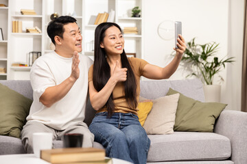 A relaxed couple enjoying a casual moment taking a selfie while sitting comfortably on their living room sofa.