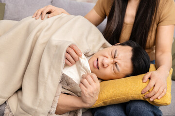 Caring Woman Comforting Sick Man Lying On Couch Under Blanket, Holding Tissue, Experiencing Flu Symptoms, Home Care, Compassion