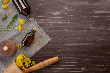 Fototapeta na wymiar Dandelion essential oil (tincture, remedy, infusion) bottle with fresh dandelion flowers. Flower essential oil. Herbal medicine. Top view, flat lay, copy space.
