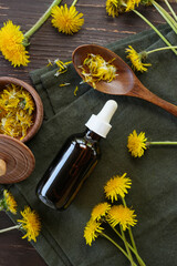 Bottles with cosmetic oil and bowls of dandelion flowers. Concrept of Herbal or homeopathy medicine. Flower essential oil. Herbal medicine. Top view, flat lay.