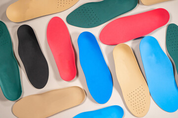 Orthopedic insoles are lined up on a wooden surface. samples of different orthopedic insoles. insoles with a variety of coating.