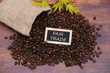 Ein Sack mit gerösteten Kaffeebohnen und dem Text Fair Trade auf einem Schild.	 - obrazy, fototapety, plakaty