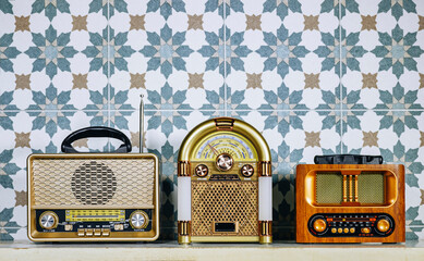 three different stylish retro radio player stands on a white wooden table. near tiles wall