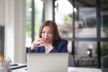 Asian businesswomen reading marketing business report and finance chart on laptop to thinking about strategy of new business while analyze investment and market stock of new startup in outside office - 784334303