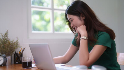 Young asian student women using technology laptop to studying and watching lecture webinar in online class while writing information in notebook and learning knowledge remote education from home - 784334936